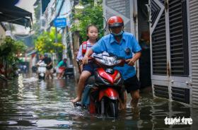 Quận 7 ngập cả mét vì triều cường, người phải ở khách sạn, người cõng con đi học