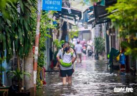 Quận 7 ngập cả mét vì triều cường, người phải ở khách sạn, người cõng con đi học